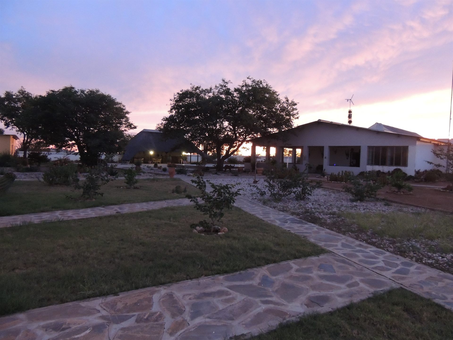 Wildlife Lodge SATURN im rosa Abendlicht — Hauptgebäude, Lapa und Garten im weiten Damaraland